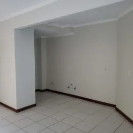 Corredor interno com paredes brancas e piso de cerâmica.