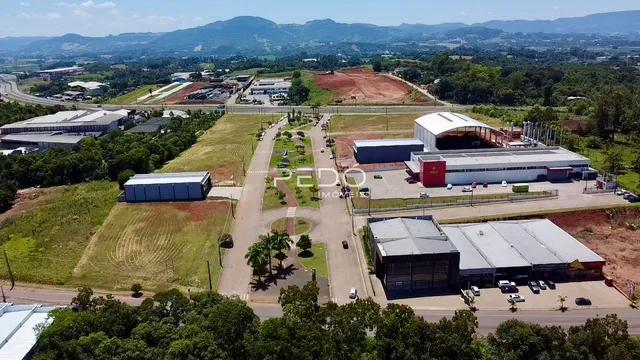Vista aérea de uma propriedade rural com grandes áreas de terra e edifícios industriais.