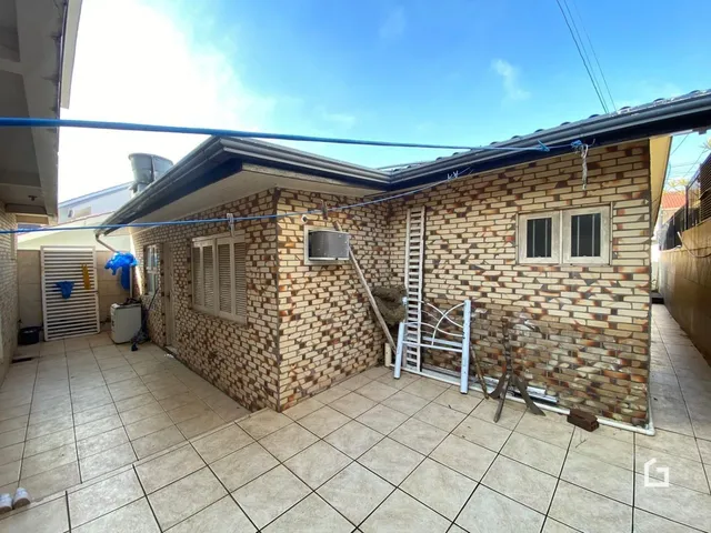 Fachada de casa em tijolo aparente com piso de cerâmica na área externa.