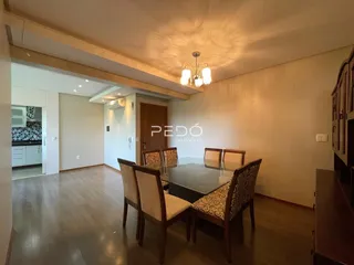 Foto de uma sala de jantar com mesa e cadeiras de madeira em um imóvel no Brasil.
