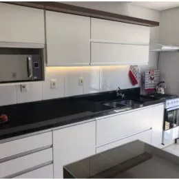 Foto de uma cozinha com armários brancos e bancada escura.