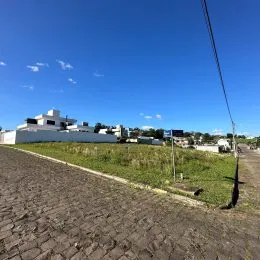 Vista de uma estrada de terra e campo aberto sob um céu azul.