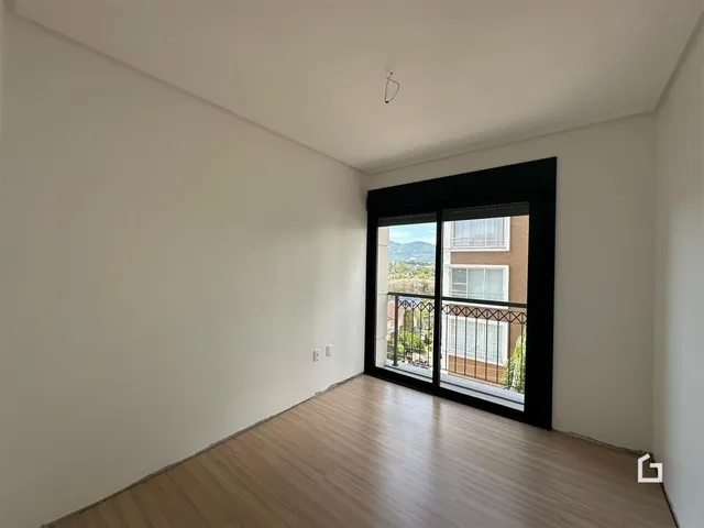 Interior de um ambiente com piso de madeira e vista para o exterior.
