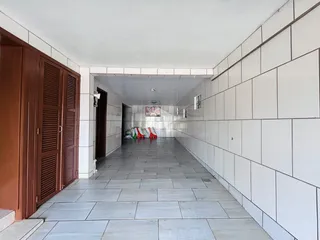 Corredor interno com piso de azulejo claro e paredes brancas.
