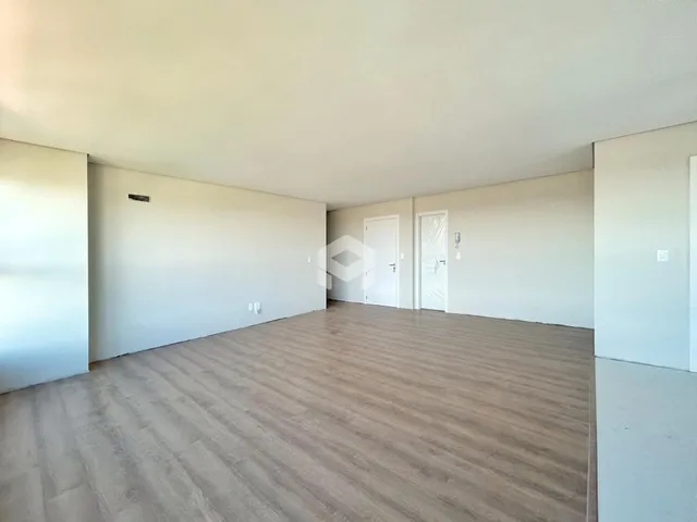 Vista interna de um ambiente com piso de madeira clara e paredes brancas.