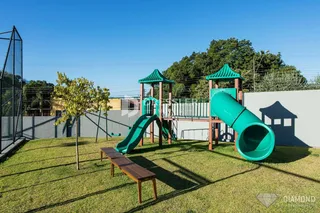 Quintal gramado com playground e banco de madeira.