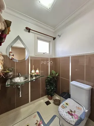 Foto de um banheiro com revestimento de cerâmica marrom e louças sanitárias.