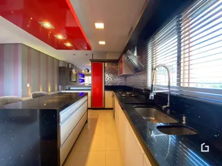 Cozinha moderna com armários brancos e bancadas escuras em um imóvel no Brasil.