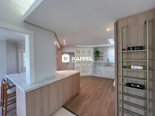 A foto mostra uma sala de estar moderna com ilha de cozinha e armários em madeira.