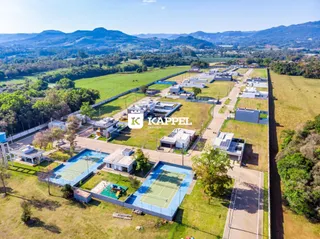 Vista aérea de um conjunto residencial com várias casas e quadras esportivas em Lajeado.