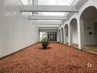 Vista de um pátio interno com piso de cascalho avermelhado.