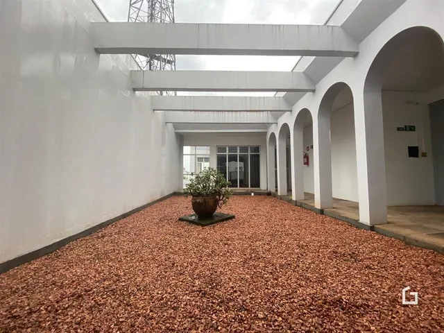 Vista de um pátio interno com piso de cascalho avermelhado.