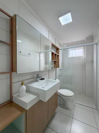 Banheiro moderno com box de vidro e revestimento branco.
