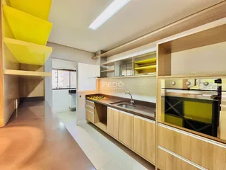 Interior de uma cozinha com armários de madeira e bancada.