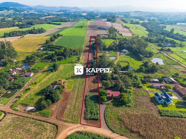 Vista aérea de uma propriedade rural com extensos campos e vegetação ao redor.