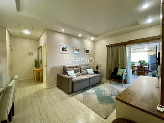 Sala de estar com sofá e piso de cerâmica clara em um imóvel no Brasil.