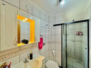 Foto de um banheiro com azulejos brancos e box de vidro.