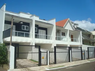 Fachada de uma residência branca com portão de metal na rua.