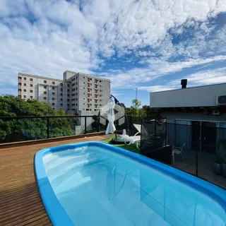 Uma piscina azul com deck de madeira está visível em uma área externa.