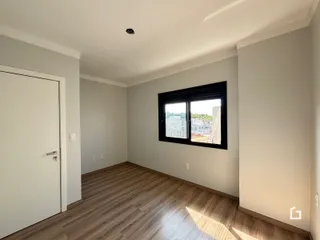 Ambiente interno com piso de madeira clara e janela grande.