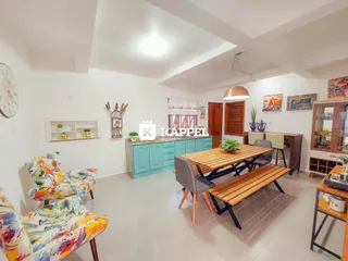 Uma sala de jantar com mesa de madeira e cadeiras em um ambiente claro.
