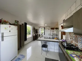 Cozinha moderna com armários brancos e piso de cerâmica clara.