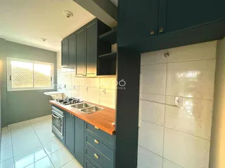 Vista da cozinha com armários escuros e piso claro em imóvel no Brasil.