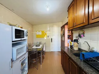 Interior de uma cozinha com armários de madeira e eletrodomésticos brancos.