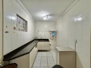 Imagem de uma cozinha com revestimento de cerâmica branca e bancada escura.