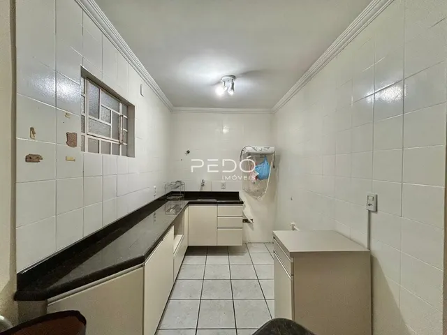 Imagem de uma cozinha com revestimento de cerâmica branca e bancada escura.