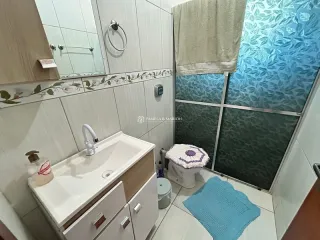 Banheiro com pia branca e revestimento cerâmico.