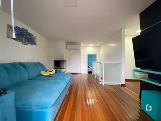 Sala de estar com sofá azul e piso de madeira.