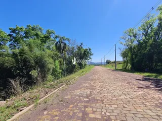 Uma estrada de paralelepípedos atravessa uma paisagem verde sob um céu azul.