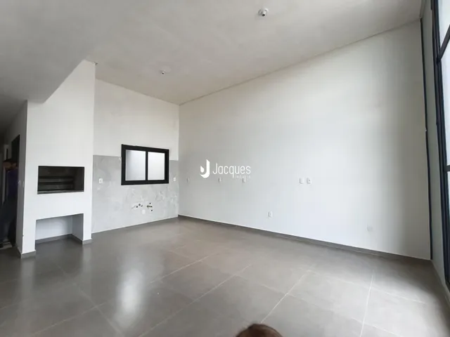 Foto de um ambiente interno com paredes brancas e piso de concreto.