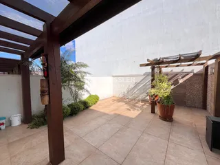 Vista de uma área externa com piso de cerâmica e estrutura de madeira.