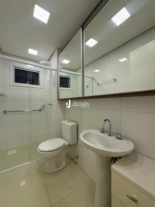 Foto de um banheiro interno com azulejos brancos e louças sanitárias.