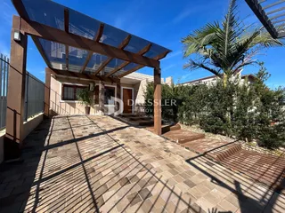 Vista da área externa com piso de tijolos e estrutura de pérgola.