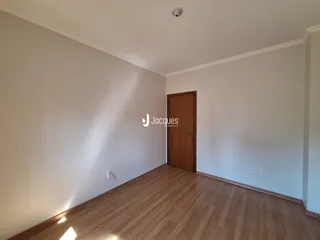 Um corredor interno com piso de madeira e paredes brancas.