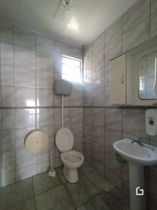 Foto de um banheiro com azulejos brancos e louças sanitárias.