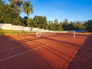 Uma vista de uma quadra esportiva externa com grama e árvores ao fundo.