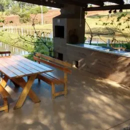 Uma área externa com mesa e bancos de madeira em um jardim.
