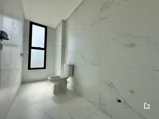 Foto de um banheiro com paredes de mármore branco e piso claro.