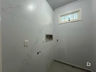 Parede interna com revestimento de mármore branco e janela.