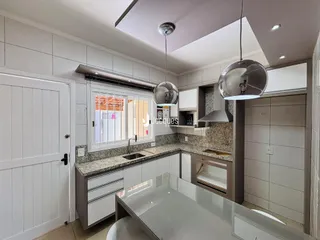 Vista interna de uma cozinha moderna com armários brancos e bancadas claras.