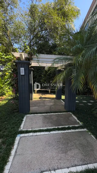 Vista da entrada de uma propriedade em Lajeado, Brasil, com paisagismo verde.