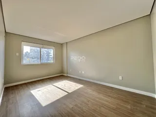 Ambiente interno de uma sala com piso de madeira clara e paredes neutras.