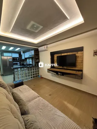 Sala de estar moderna com sofá e televisão montada em parede de madeira.