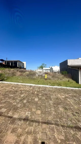 Vista externa do terreno com área pavimentada e vegetação seca.