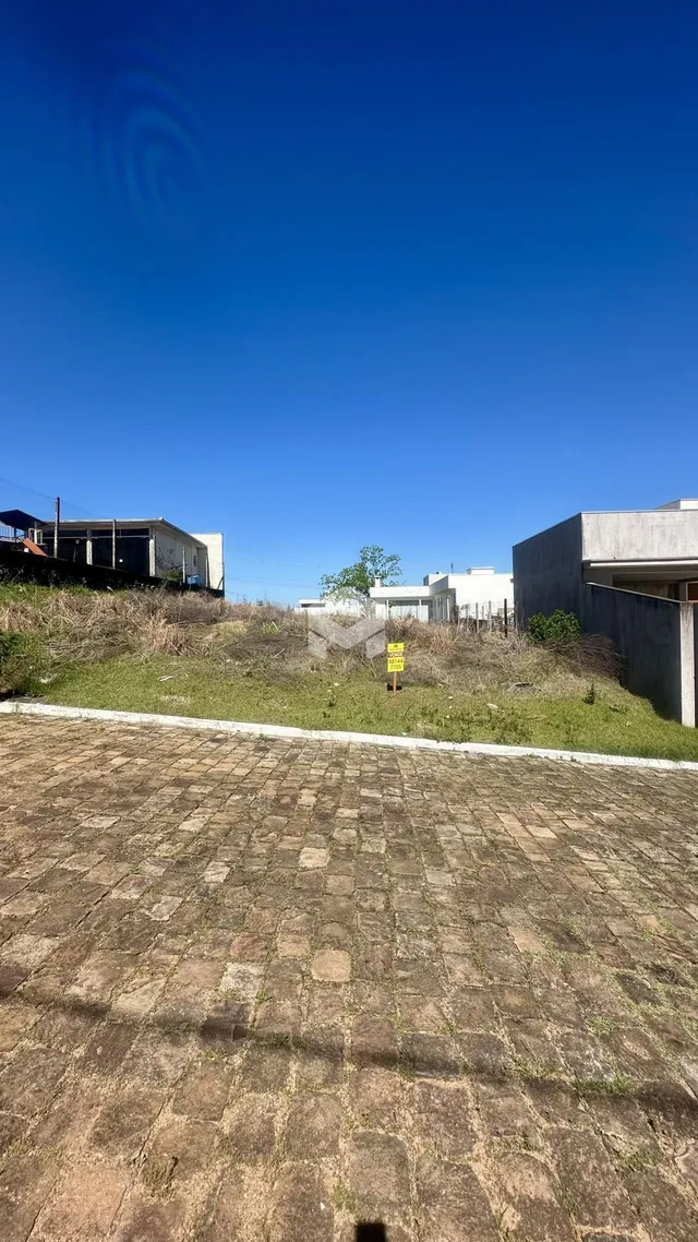Vista externa do terreno com área pavimentada e vegetação seca.