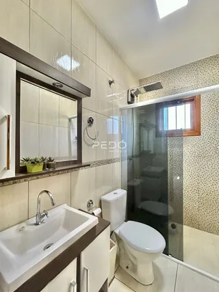 Foto de um banheiro com azulejos brancos e box de vidro.